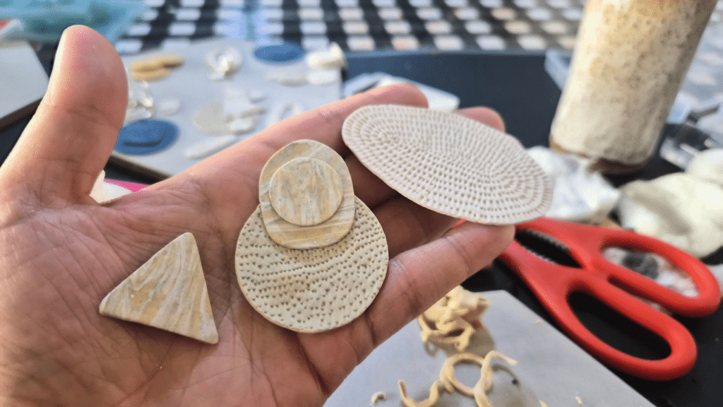 Work-in-progress bridal earrings in off-white and ecru polymer clay on the studio worktable.